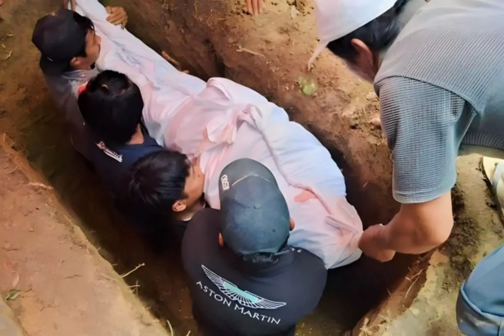 three men are lowering the dead body into the grave